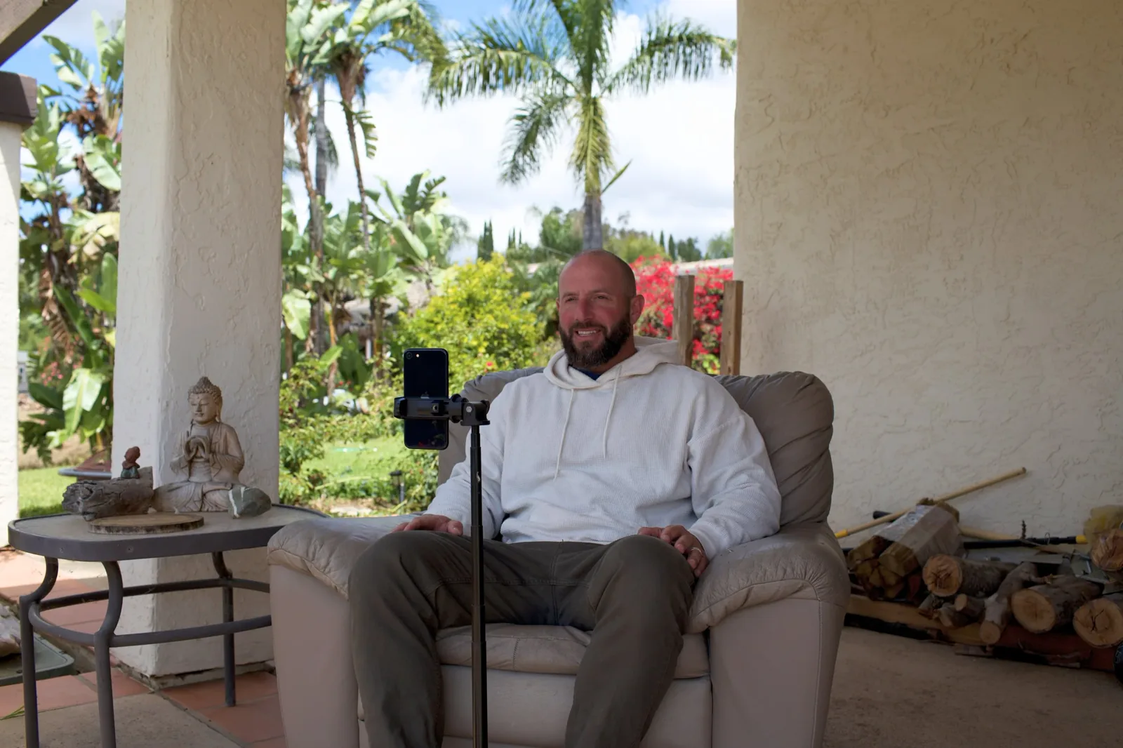 Miles on a video call, phone on a tripod, sitting on a covered porch