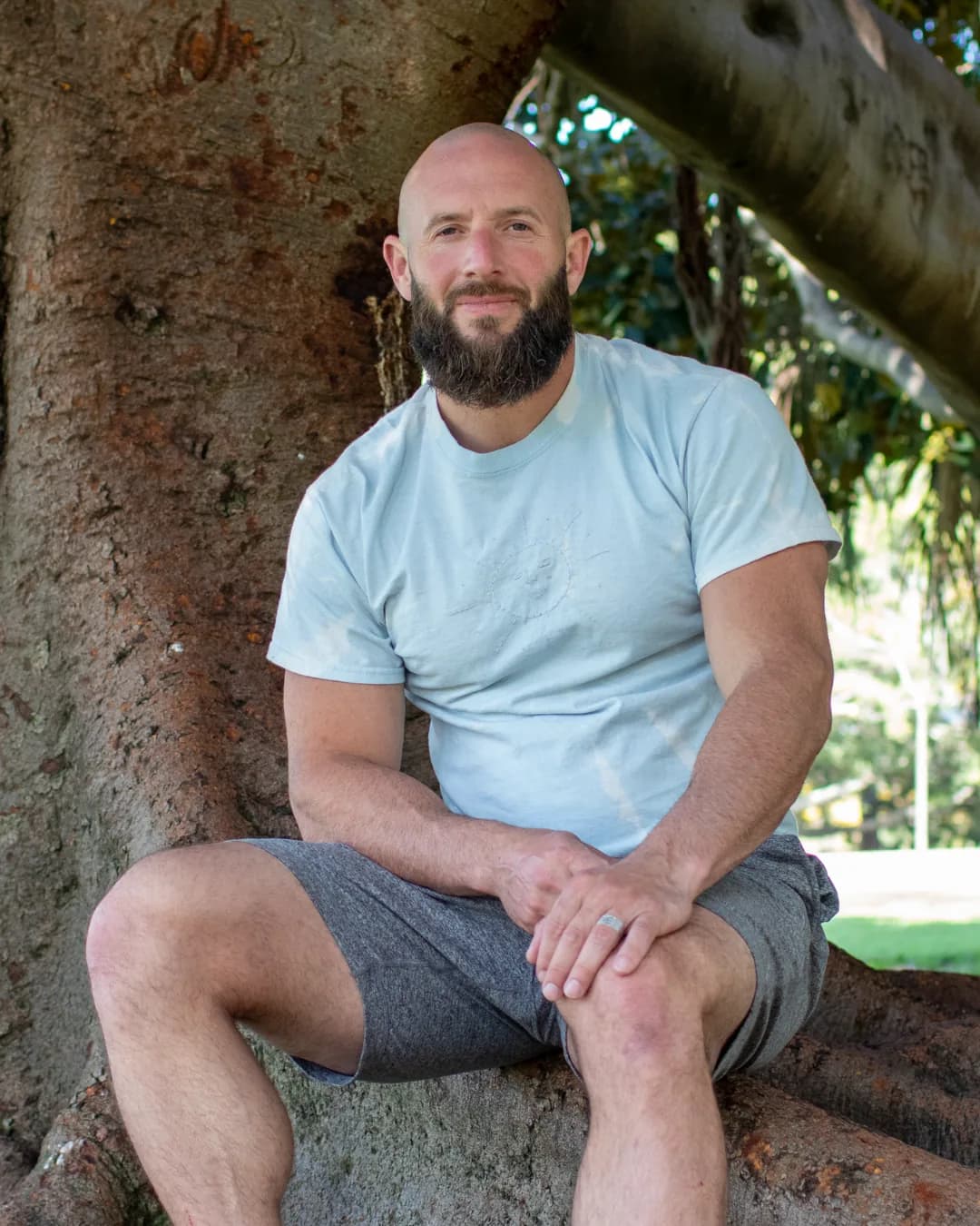 Miles Bolden sitting against a tree trunk, looking at the camera